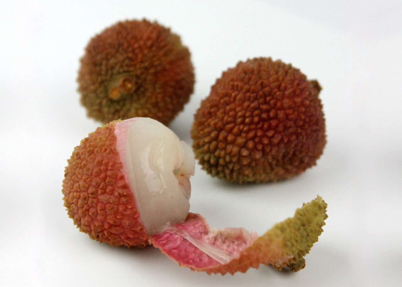 Three lychee fruits, one of which is peeled.