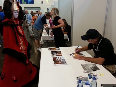 Actor John Morton signs an autograph for a fan dressed as Queen Amidala.