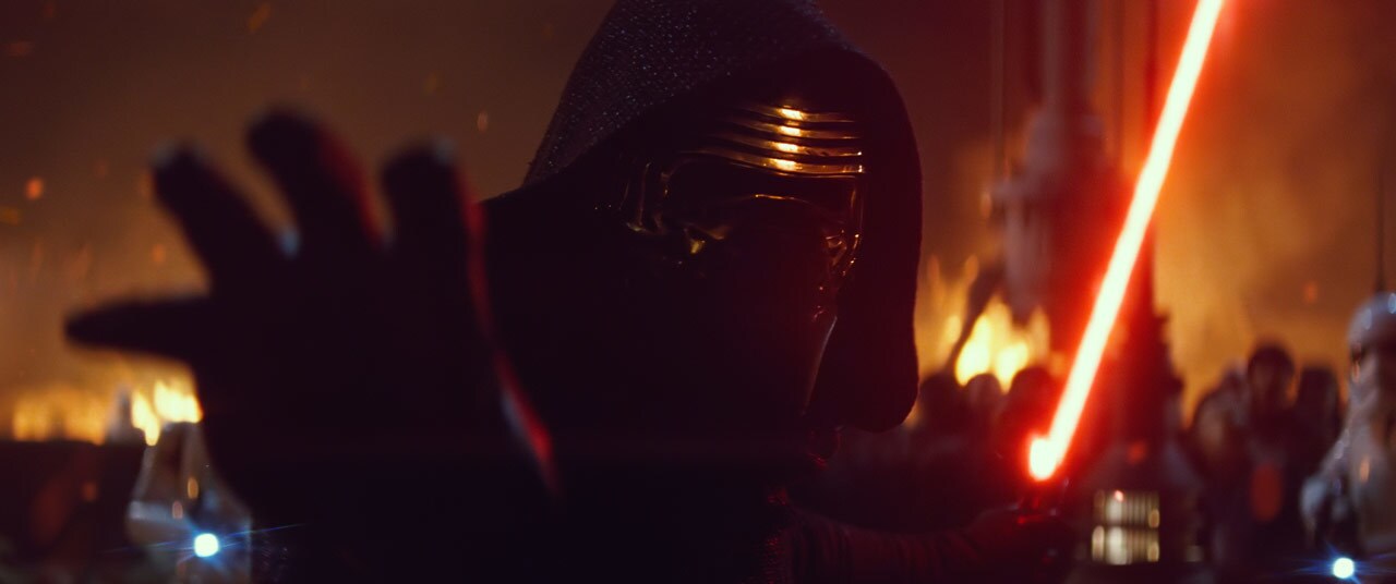 Kylo Ren reaches out with one hand while holding a lightsaber in the other, as a village burns in the background.
