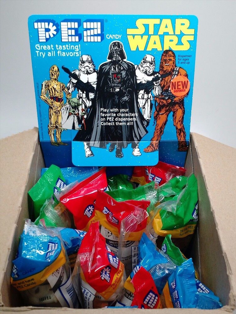 Star Wars-themed Pez dispensers are displayed in a box that features Darth Vader, Chewbacca, C-3PO, Yoda, and two stormtroopers.