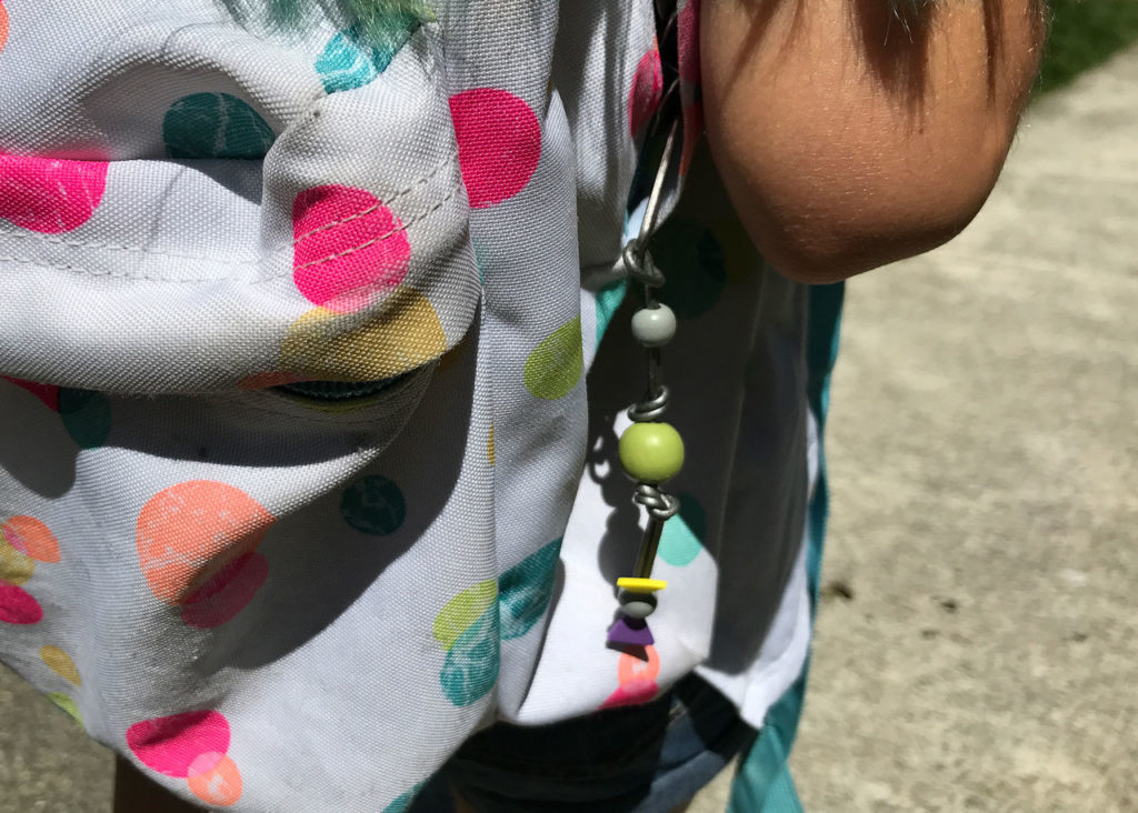 A completed homemade Ahsoka Tano silka bead charm hanging from a backpack.