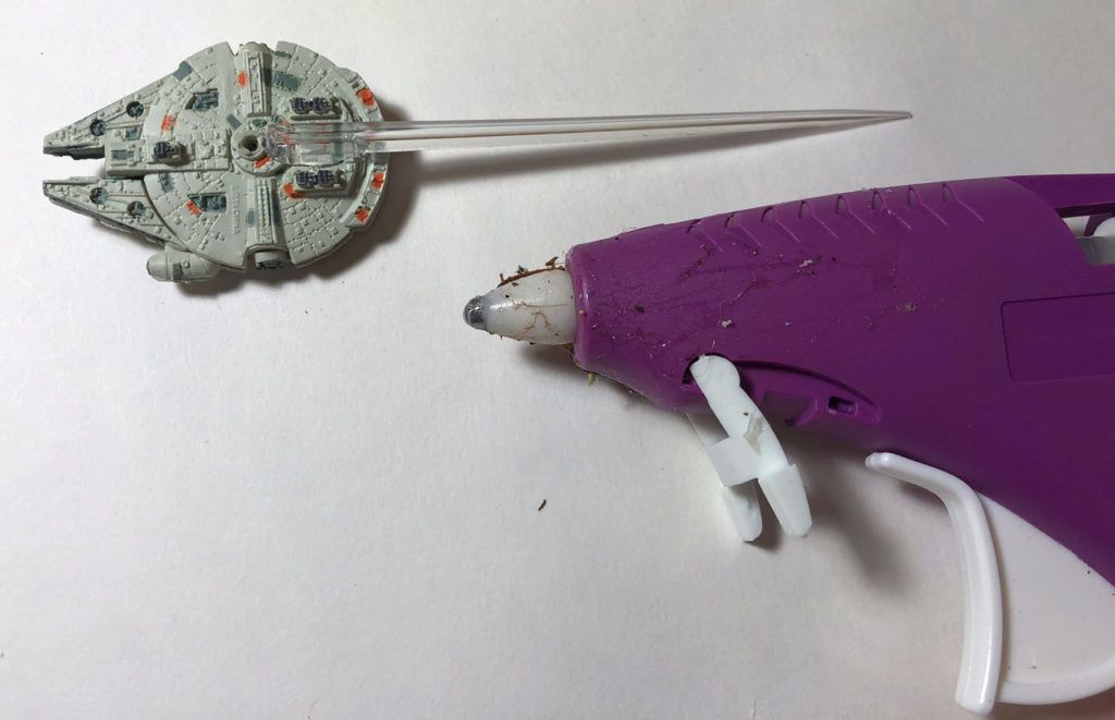 A Millennium Falcon toy next to a hot glue gun.