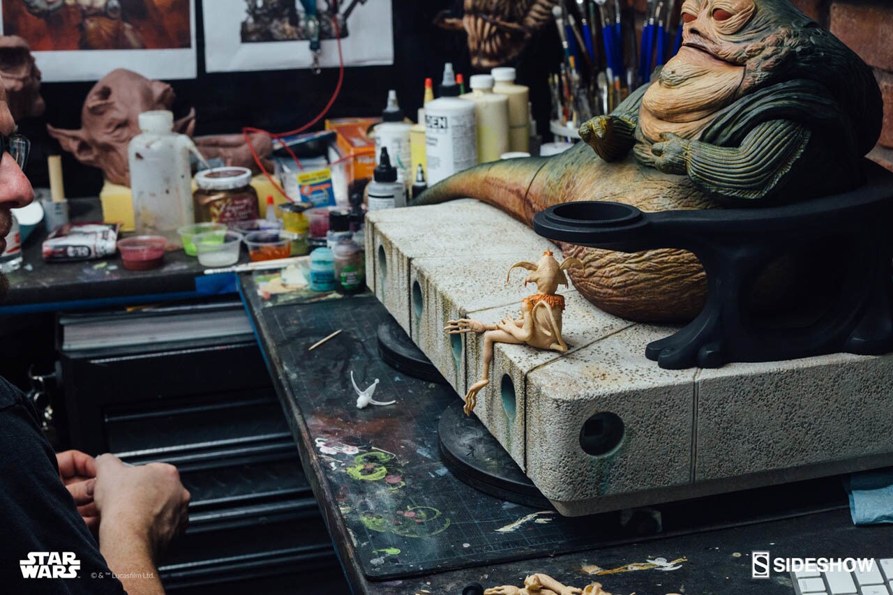 An artist works on a Jabba the Hutt and Throne Deluxe Sixth Scale Figure set in a workshop.
