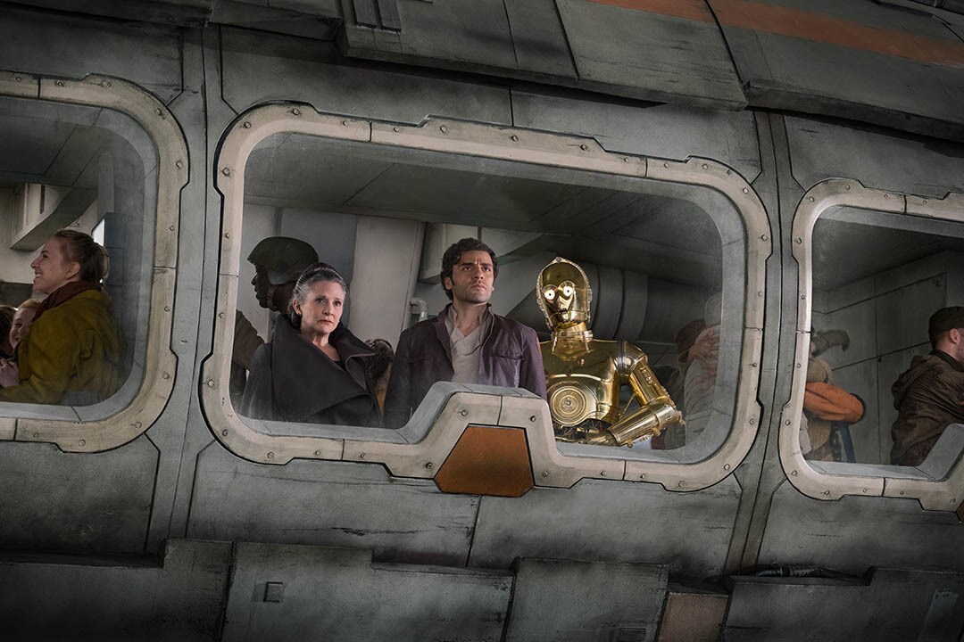 Leia, Poe, and C-3PO look out the window of a Rebel transport vehicle in The Last Jedi.