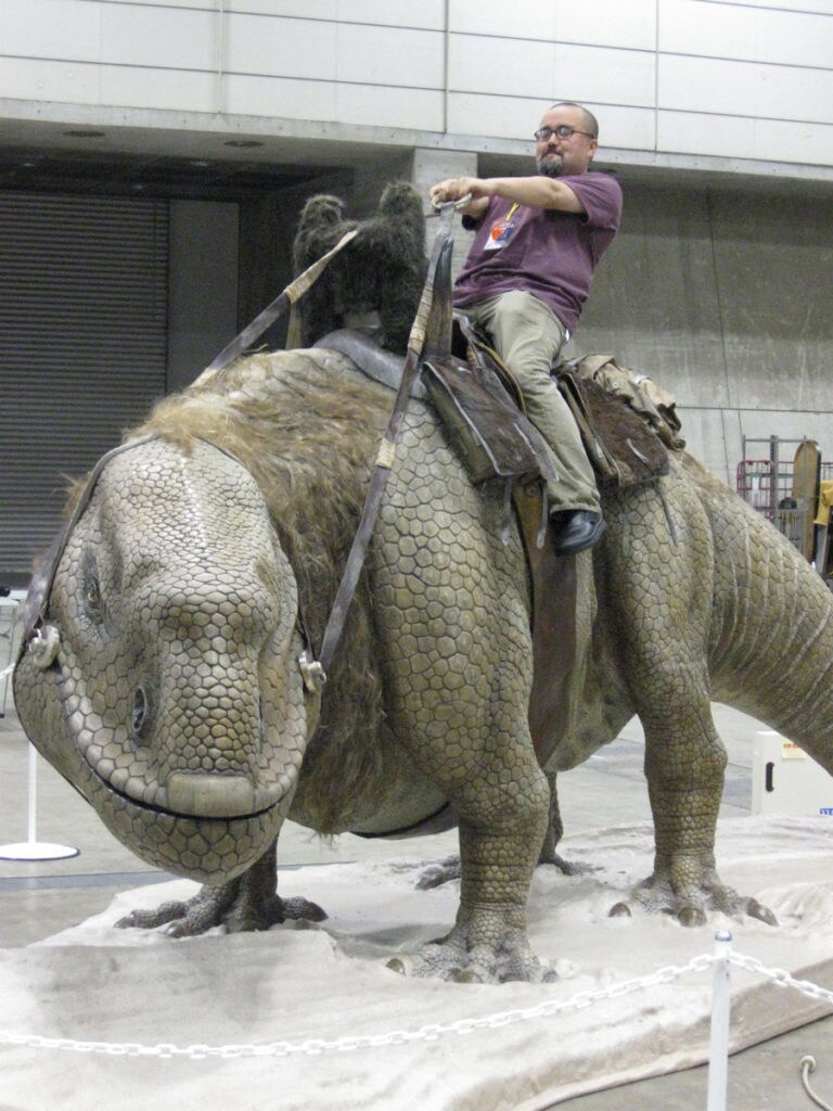 Pablo Hidalgo of Lucasfilm rides a dewback fan-made prop at Star Wars Celebration.