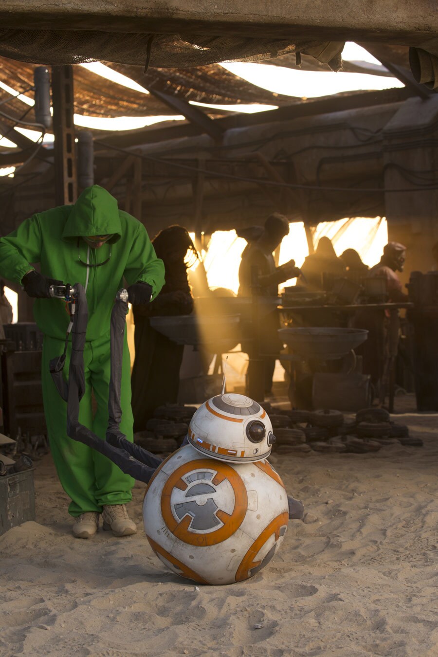 Dressed in a green sweatsuit, puppeteer Brian Herring maneuvers BB-8 while on the set of The Force Awakens..