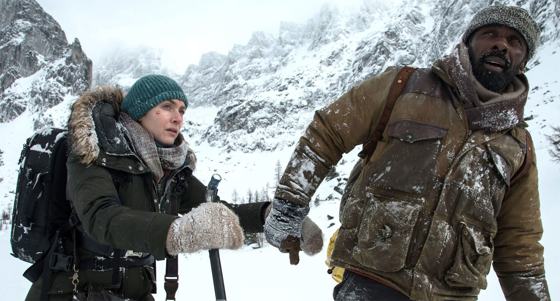 Kate Winslet (as Alex Martin) and Idris Elba (as Ben Bass) on a snowy mountain in the movie "The Mountain Between Us"