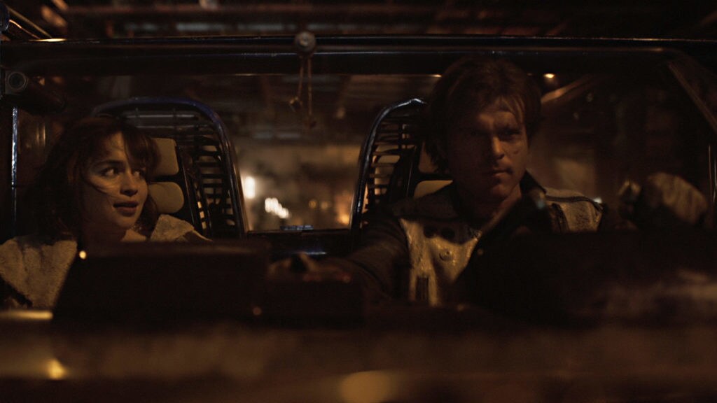 Han pilots a speeder while Qi'ra looks at him from the passenger seat in Solo: A Star Wars Story.