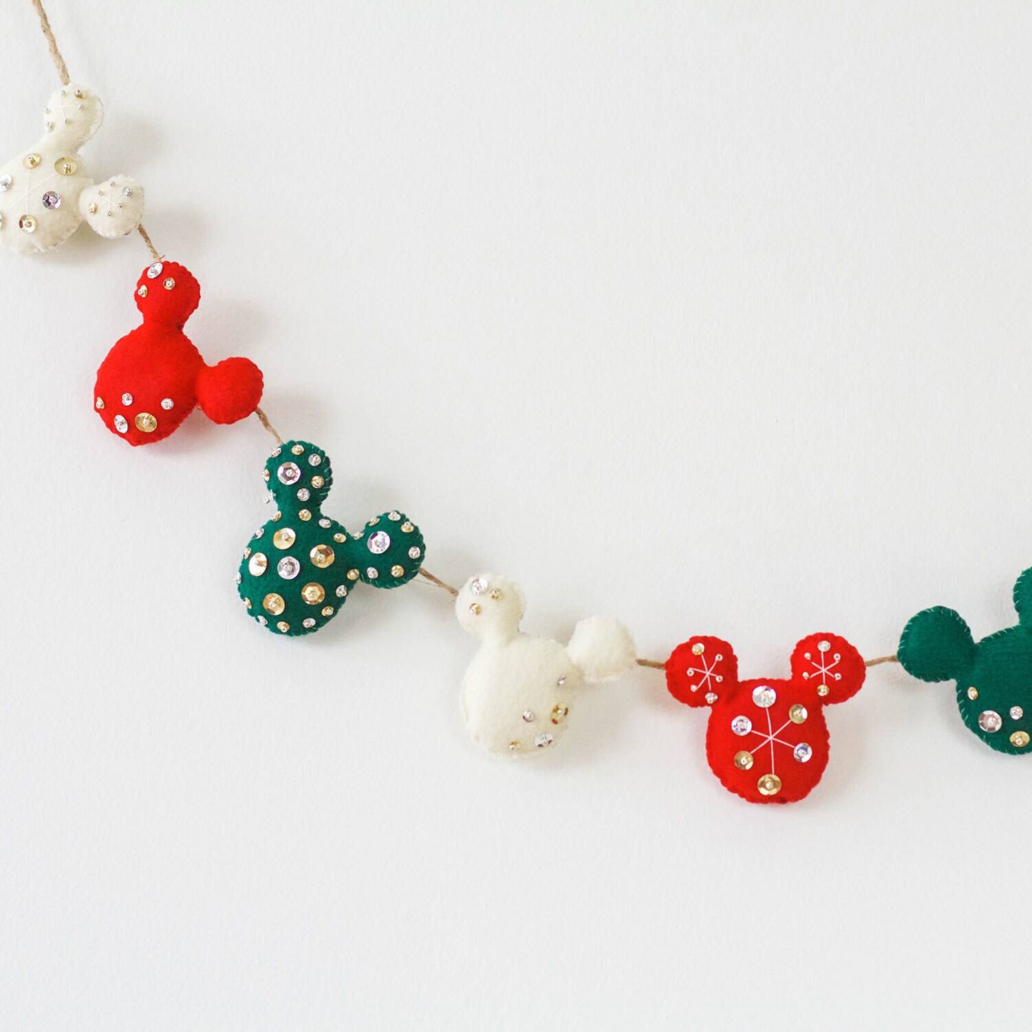 Felt Christmas themed Mickey Mouse heads decorated with sequins on a garland.