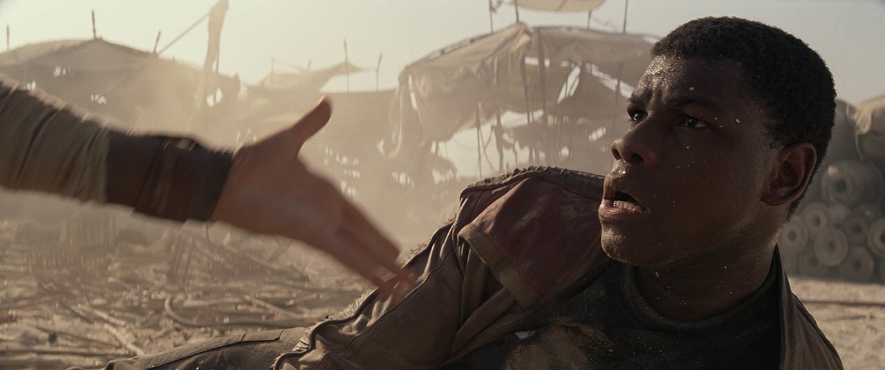 Rey offers Finn a hand.