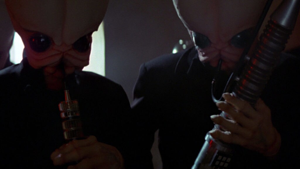 Two alien musicians play instruments in a cantina on Mos Eisley.