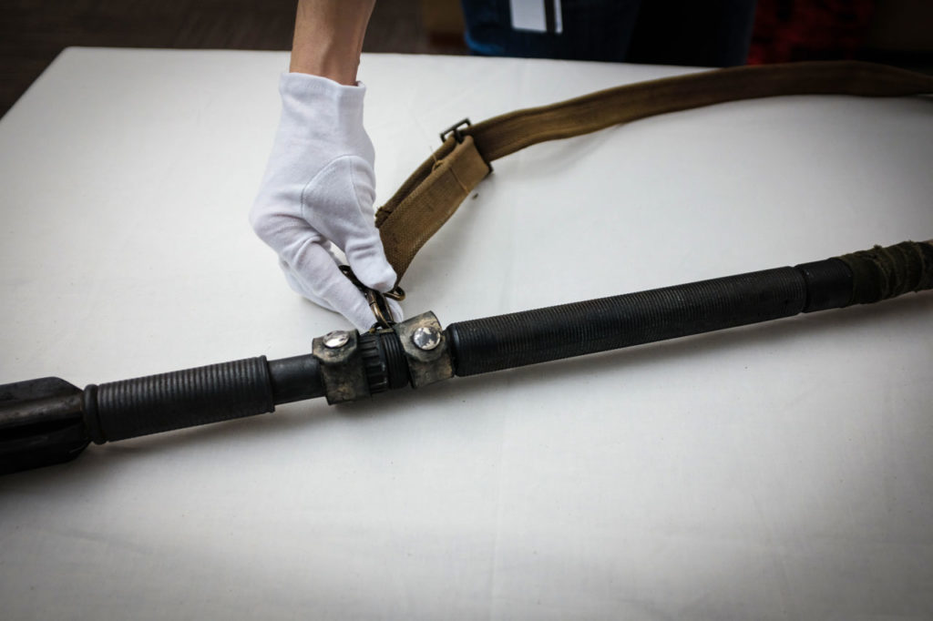 The gloved hand of Lucasfilm archivist Madlyn Burkett touches Rey's staff from The Force Awakens.