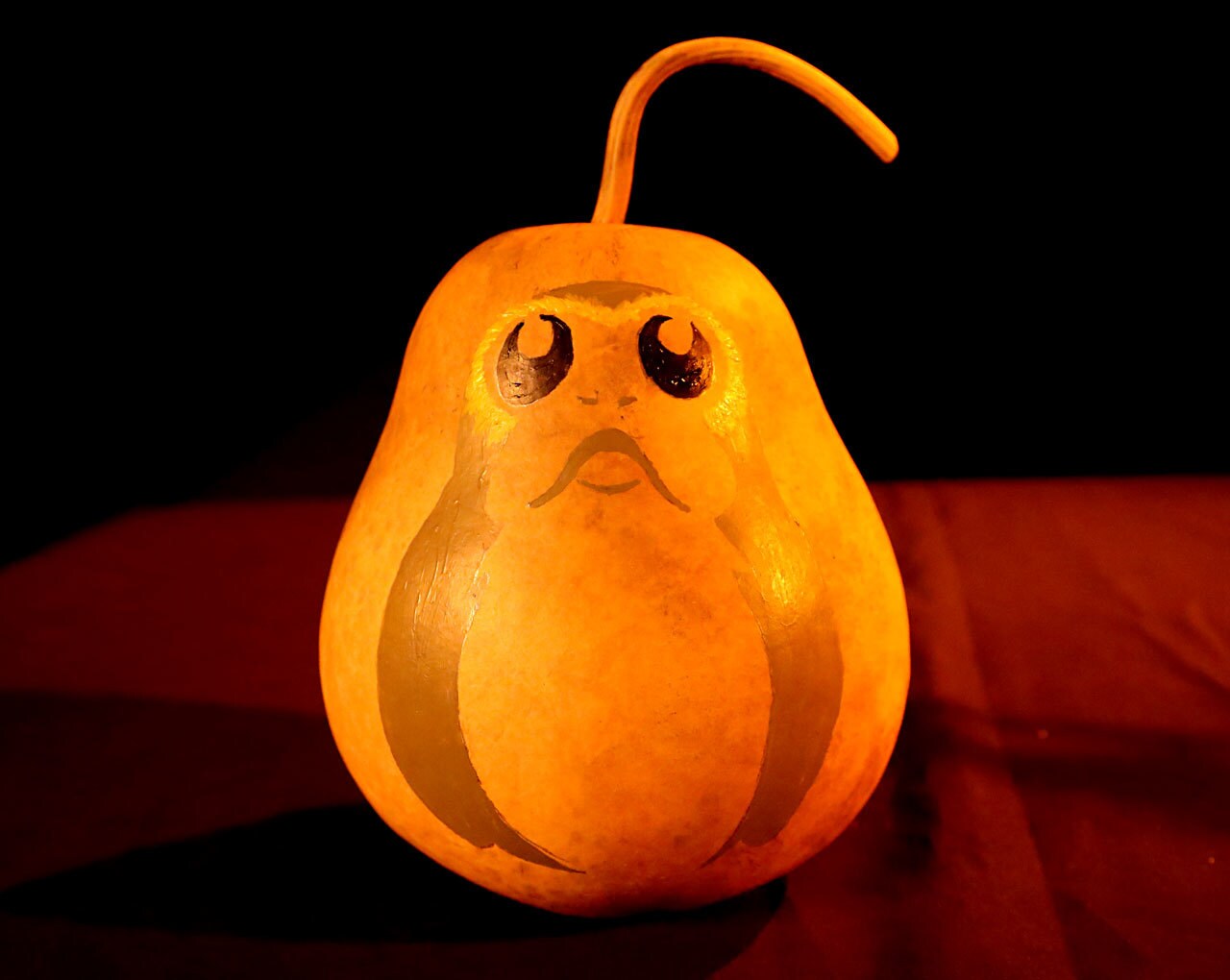 A porg painted onto a gourd using white, black, and gold acrylic paints.