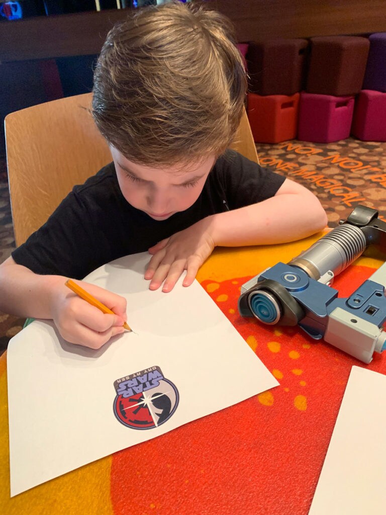 A young fan draws porgs during Star Wars Day at Sea on the Disney Fantasy.