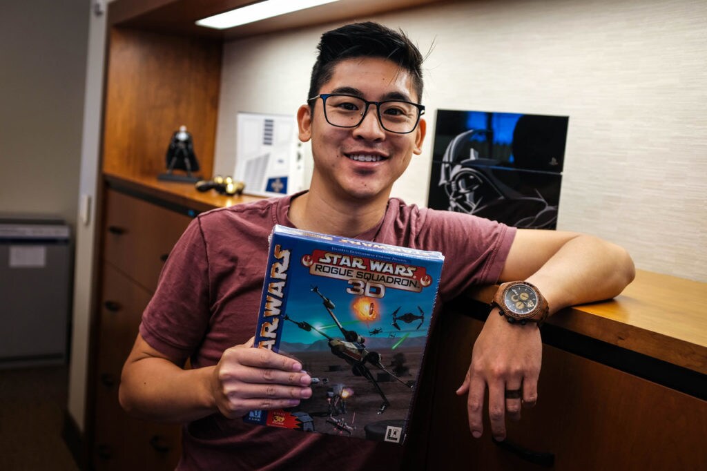 A member of the Lucasfilm Games Team holds up the box of Star Wars: Rogue Squadron.