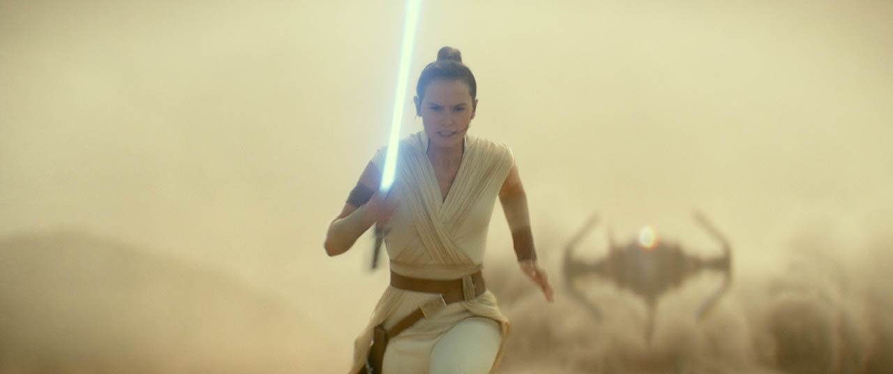 Rey wields a lightsaber while running away from an oncoming TIE fighter in The Rise of Skywalker.