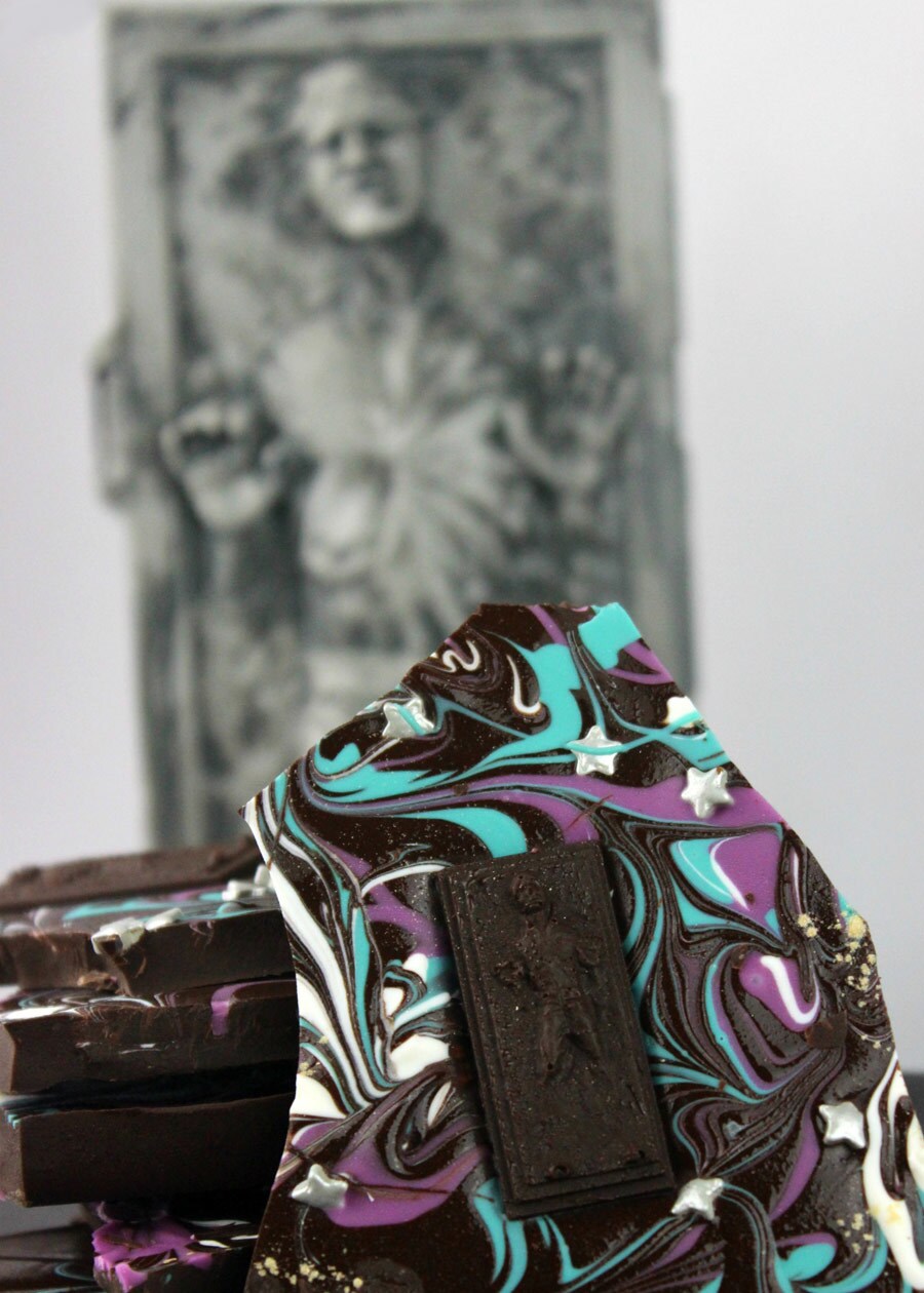 A chocolate bark dessert decorated to look like Han Solo encased in carbonite, surrounded by blue, white and purple swirl chocolate.