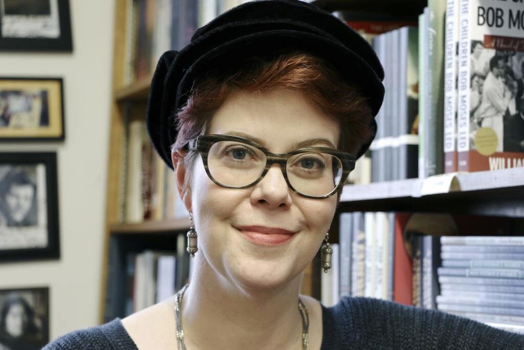 Claudia Gray, author of several Star Wars novels, smiles while standing in front of a bookcase.