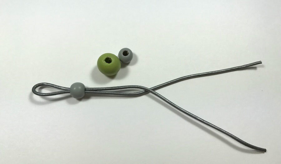 A gray leather cord folded on itself and cinched together by a bead.