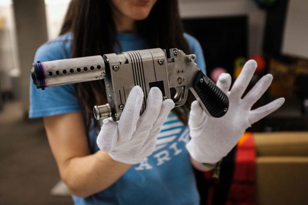 Lucasfilm archivist Madlyn Burkert holds Rey's blaster with gloved hands.