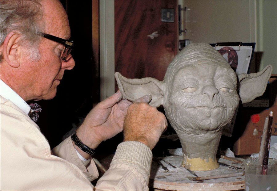 A visual effects artist works on a sculpture of Yoda's head.
