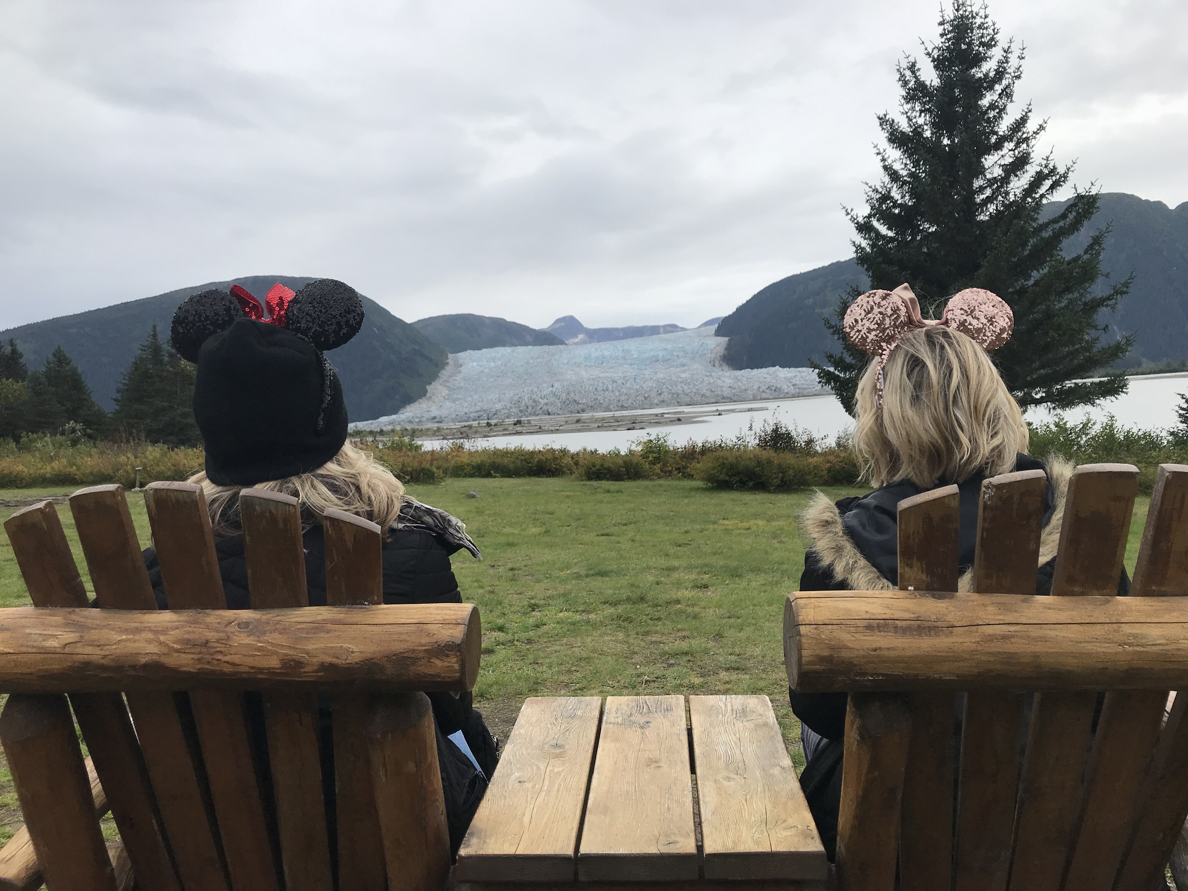 View of Taku Glacier on the Disney Wonder Alaska Cruise with two people sitting in chairs and wearing Minnie Ears