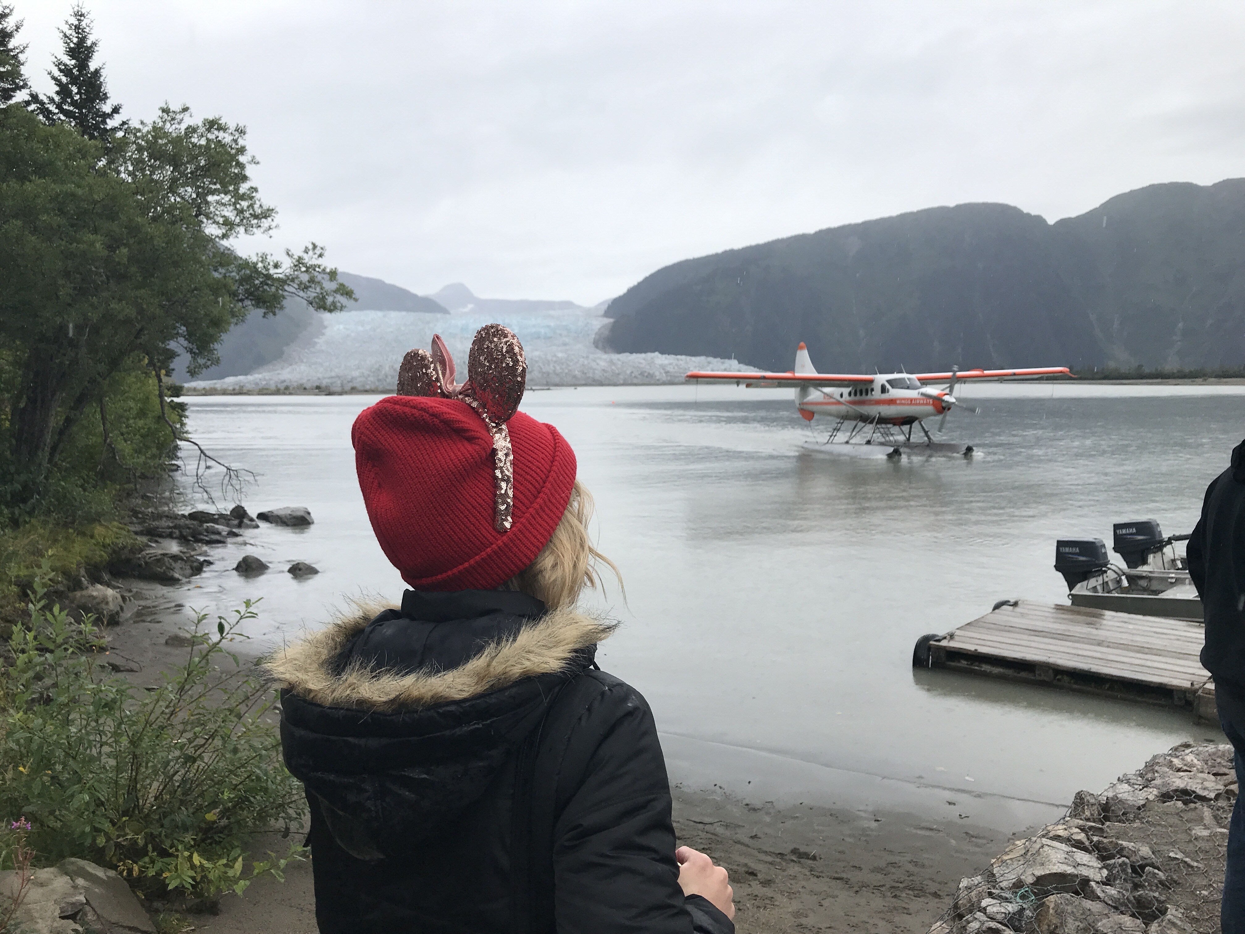 Seaplane coming in and Oh My Disney Host wearing Minnie Ears Looking out at Taku Glacier on Disney Wonder Alaska Cruise