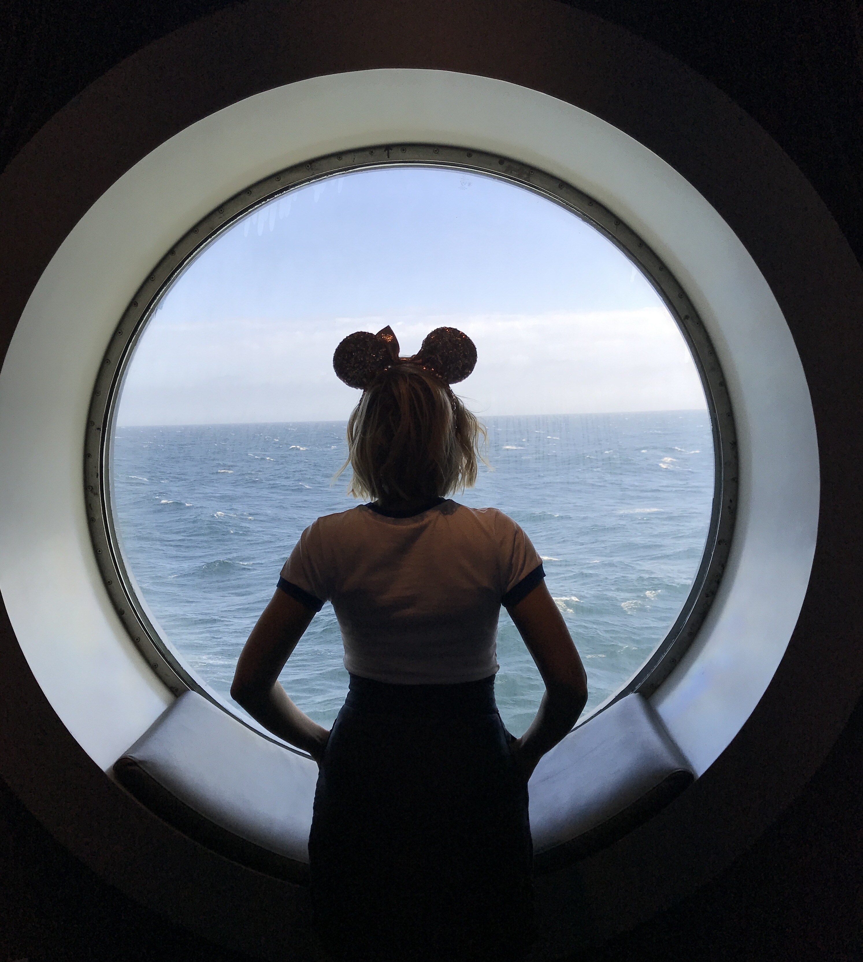 Port Hole View of the Ocean on the Disney Wonder with Oh My Disney Host and Minnie Ears
