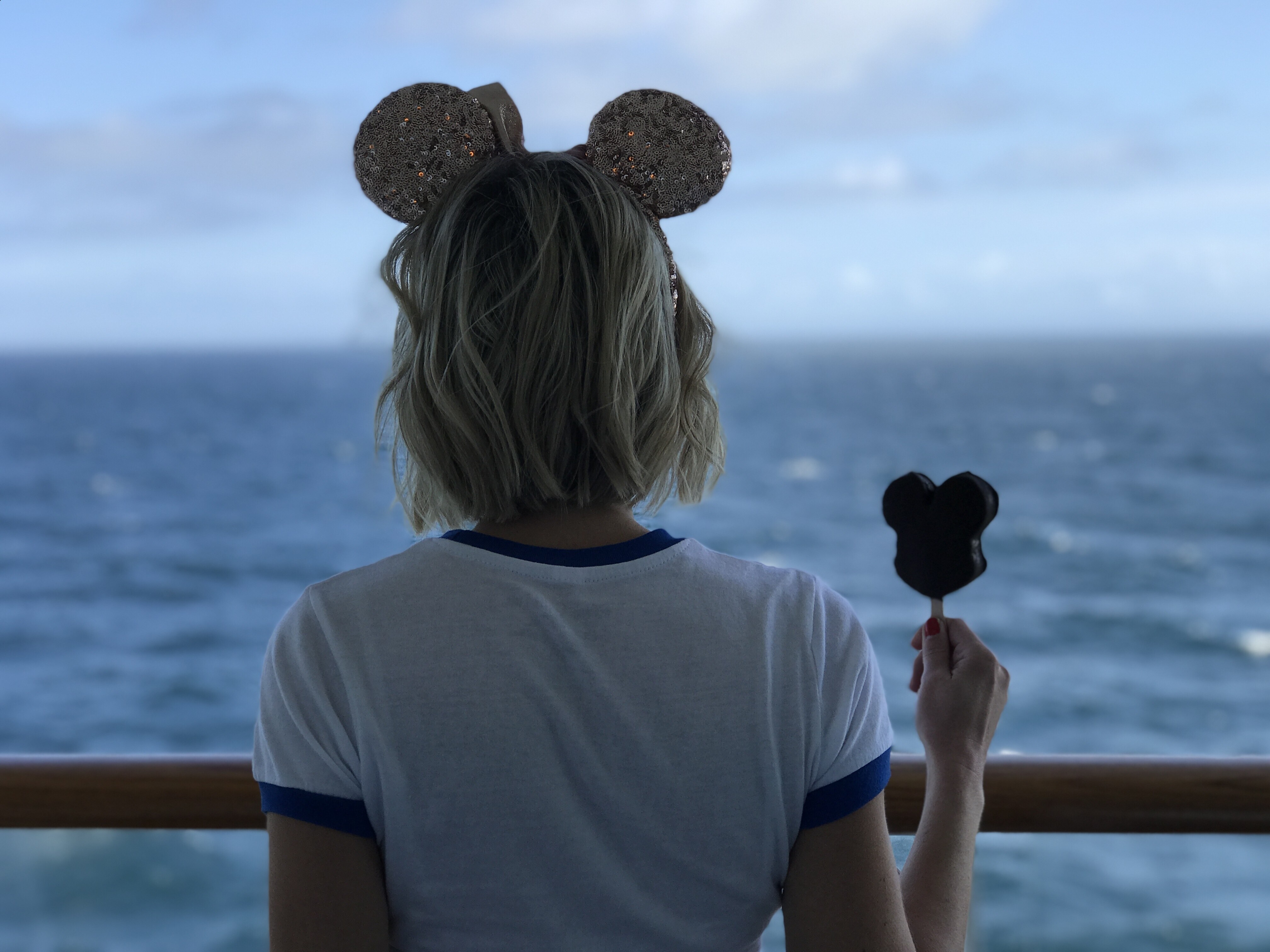 Oh My Disney Host holding Mickey Ice Cream Bar on balcony of the Disney Wonder