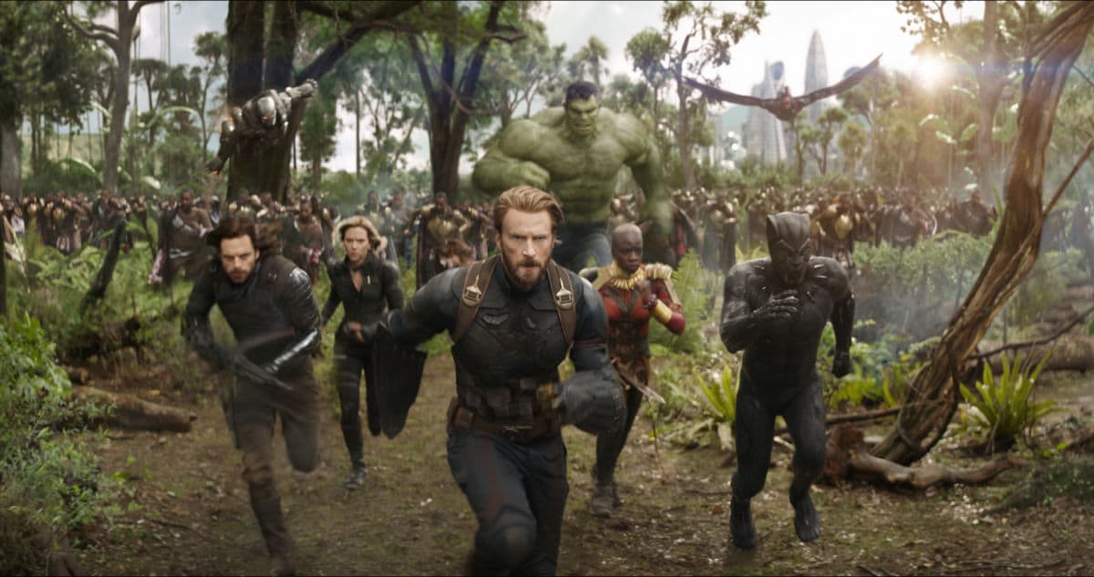 Avengers running together through a forest in a scene from the movie Avengers: Infinity War.