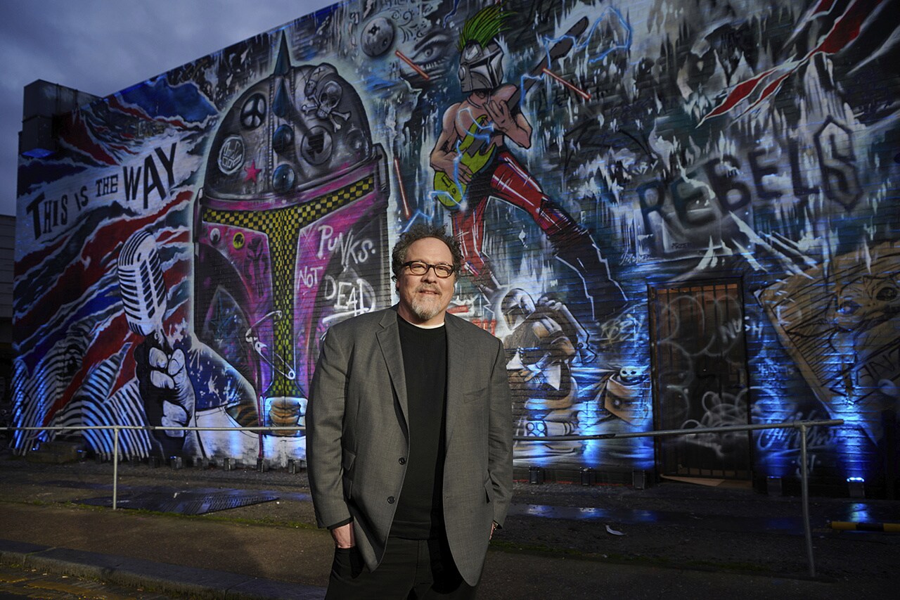 Jon Favreau in front of a Mandalorian art wall