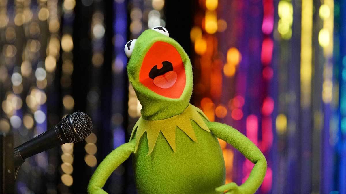 Kermit singing next to a microphone