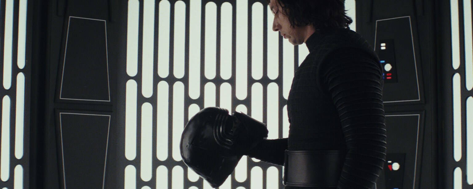 Kylo Ren looks down at his helmet.