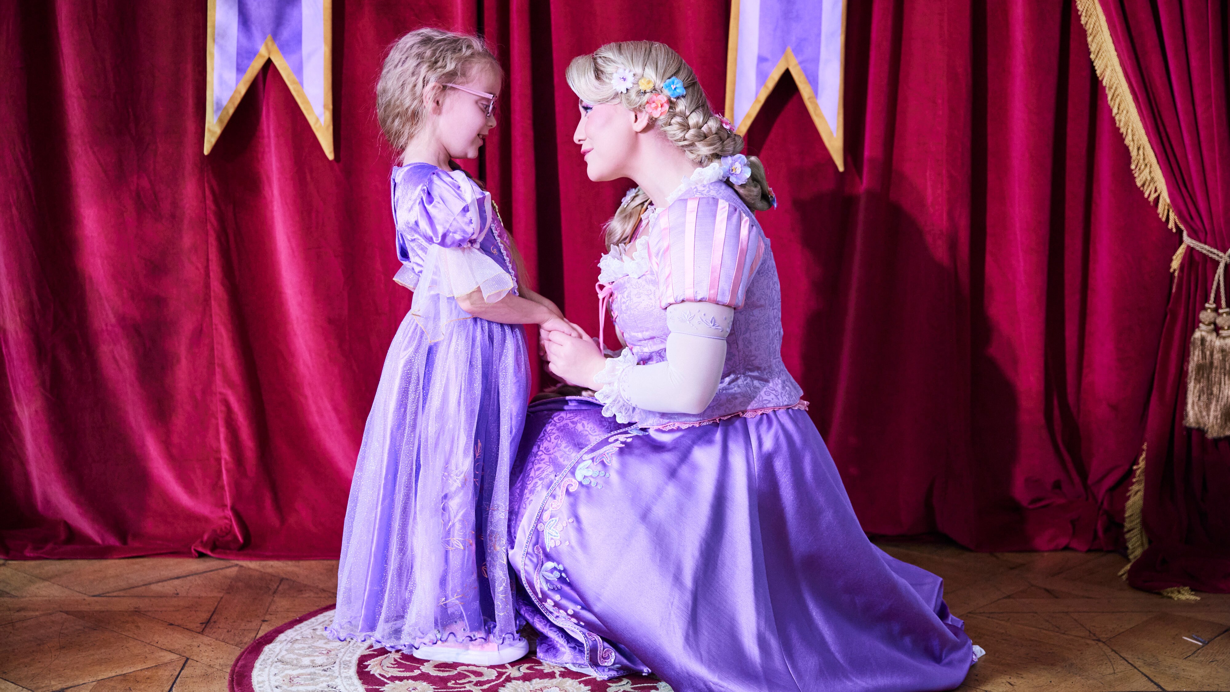 Girl in Rapunzel outfit holding hands with Rapunzel 