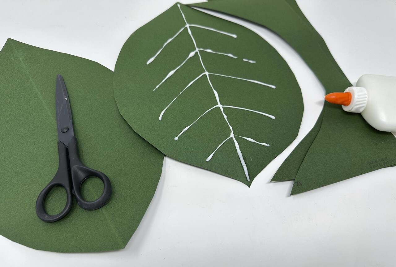 Carefully use the school glue to draw the veins of each leaf, starting on the folded line before branching out in V shapes. Let the glue dry completely.