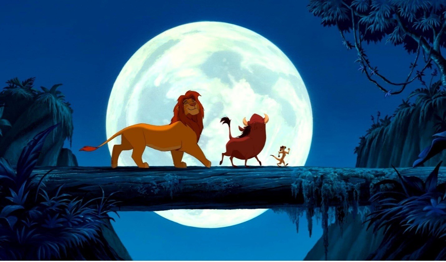 Simba, Timon and Pumbaa stroll along a log in the moonlight in The Lion King
