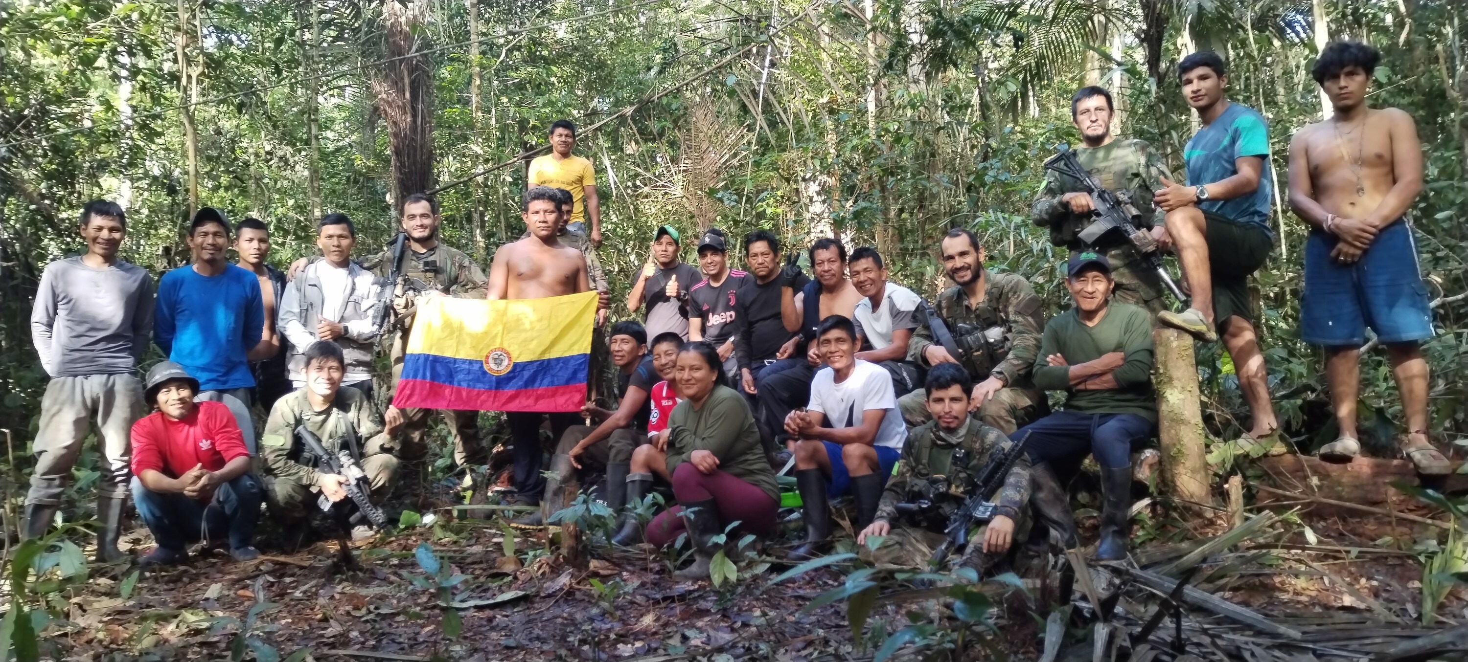 The Indigenous search team and Colombian military stand together in the jungle with the national flag. (Credit: Indigenous Rescue Team)