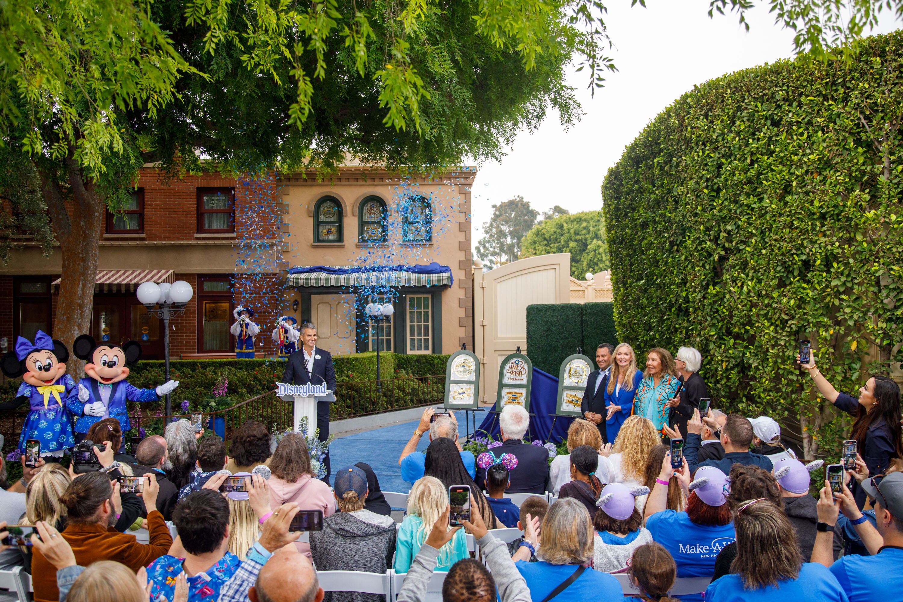 Josh D'Amaro unveils the new Main Street windows, with Mickey and Minnie on the left.