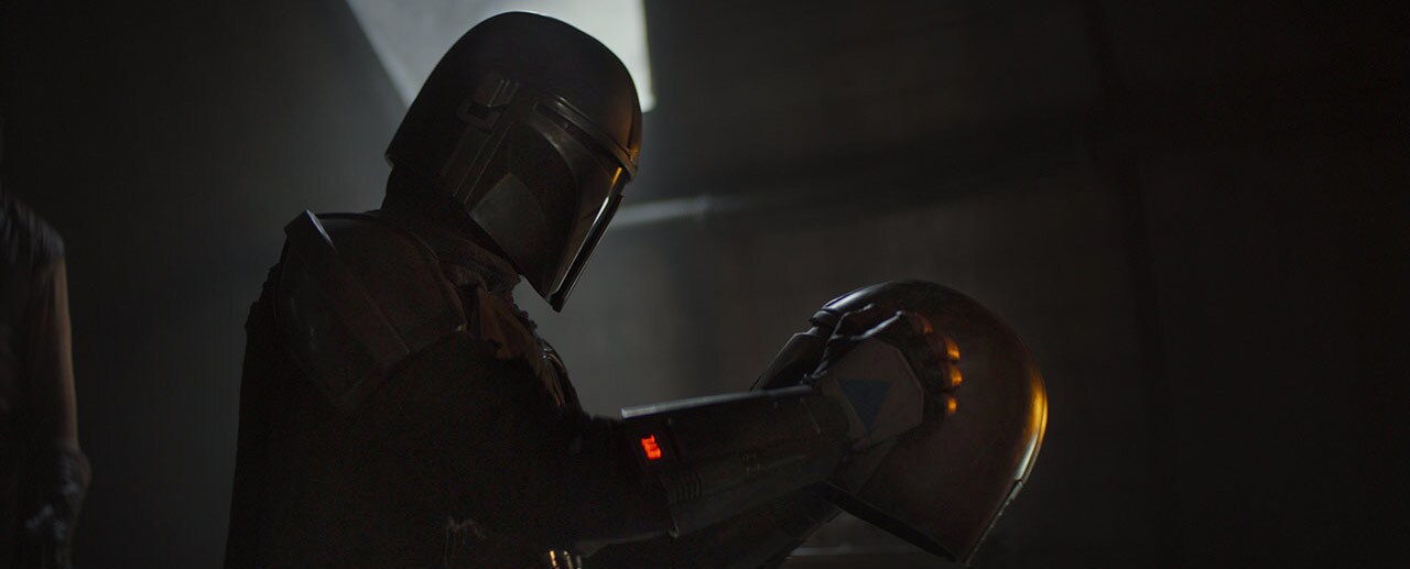 Image of Din Djarin holding a helmet.
