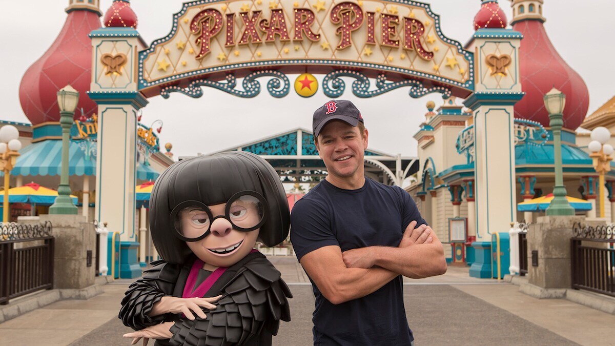 Edna Mode and Matt Damon posing in front of Pixar Pier