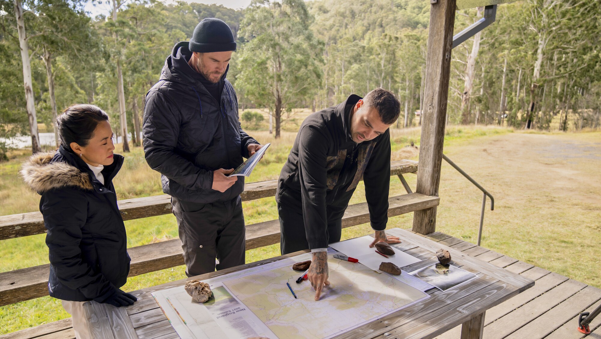 Chris Hemsworth, Otis Carey and Sharon Shah map out the route of their hike. (National Geographic for Disney+/Craig Parry)
