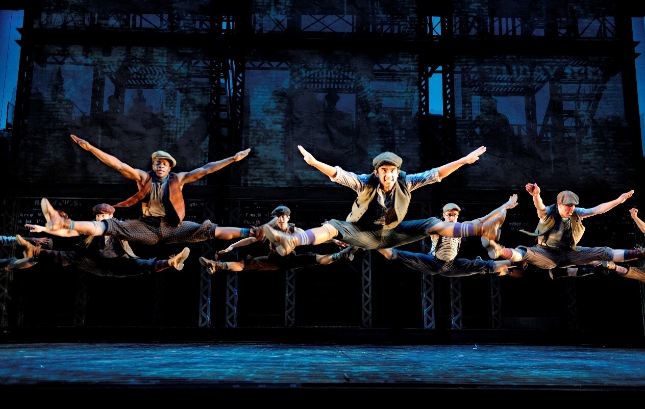 The cast of Newsies performing a dance on stage