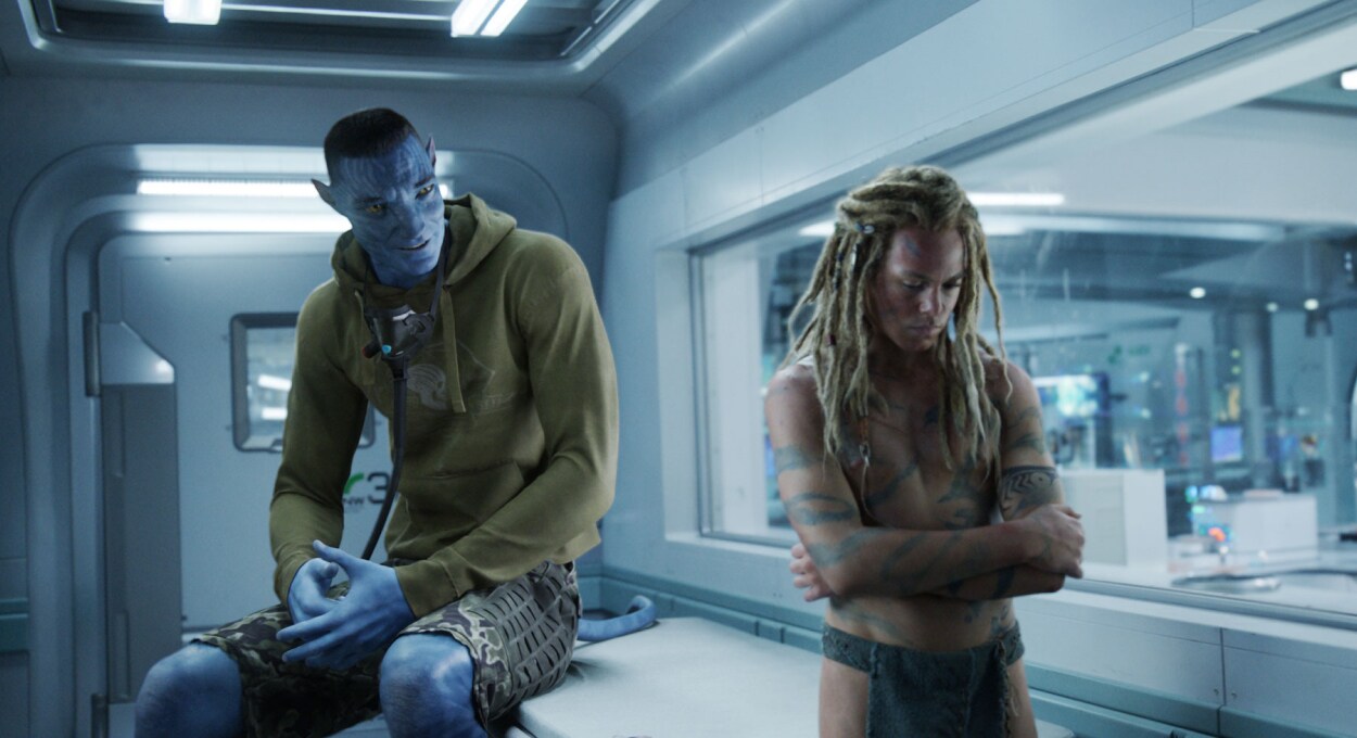 Colonel Quaritch, in recombinant form, talking to his son, Spider, who is turned away with crossed arms.