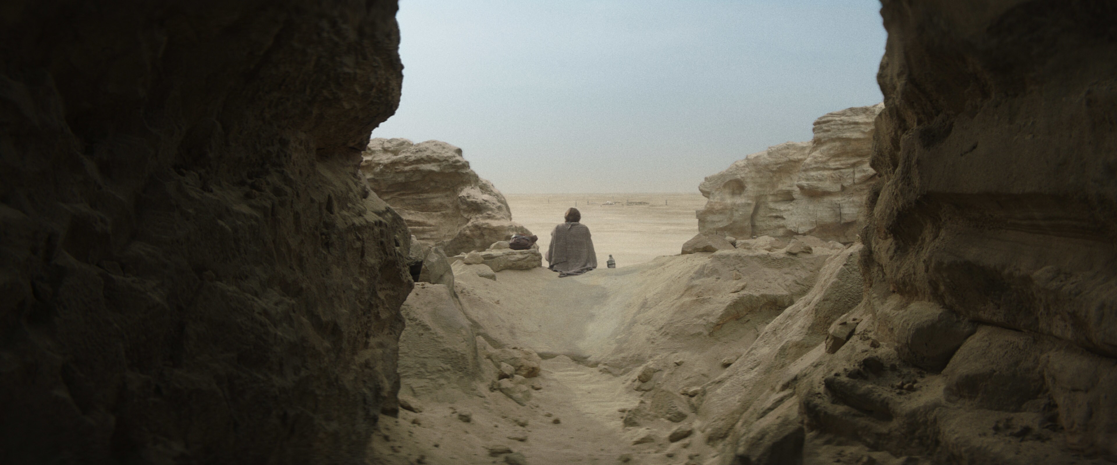 Obi-Wan Kenobi sits in a rock formation.