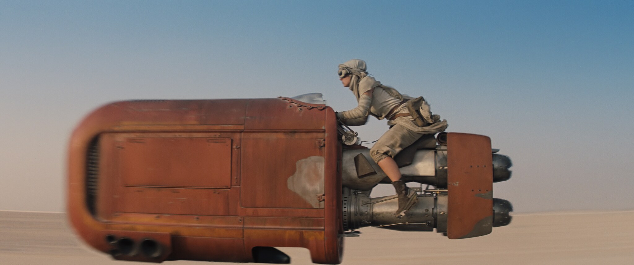 Daisy Ridley as Rey on her speeder in Jakku's desert. From the movie, "Star Wars: The Force Awakens."