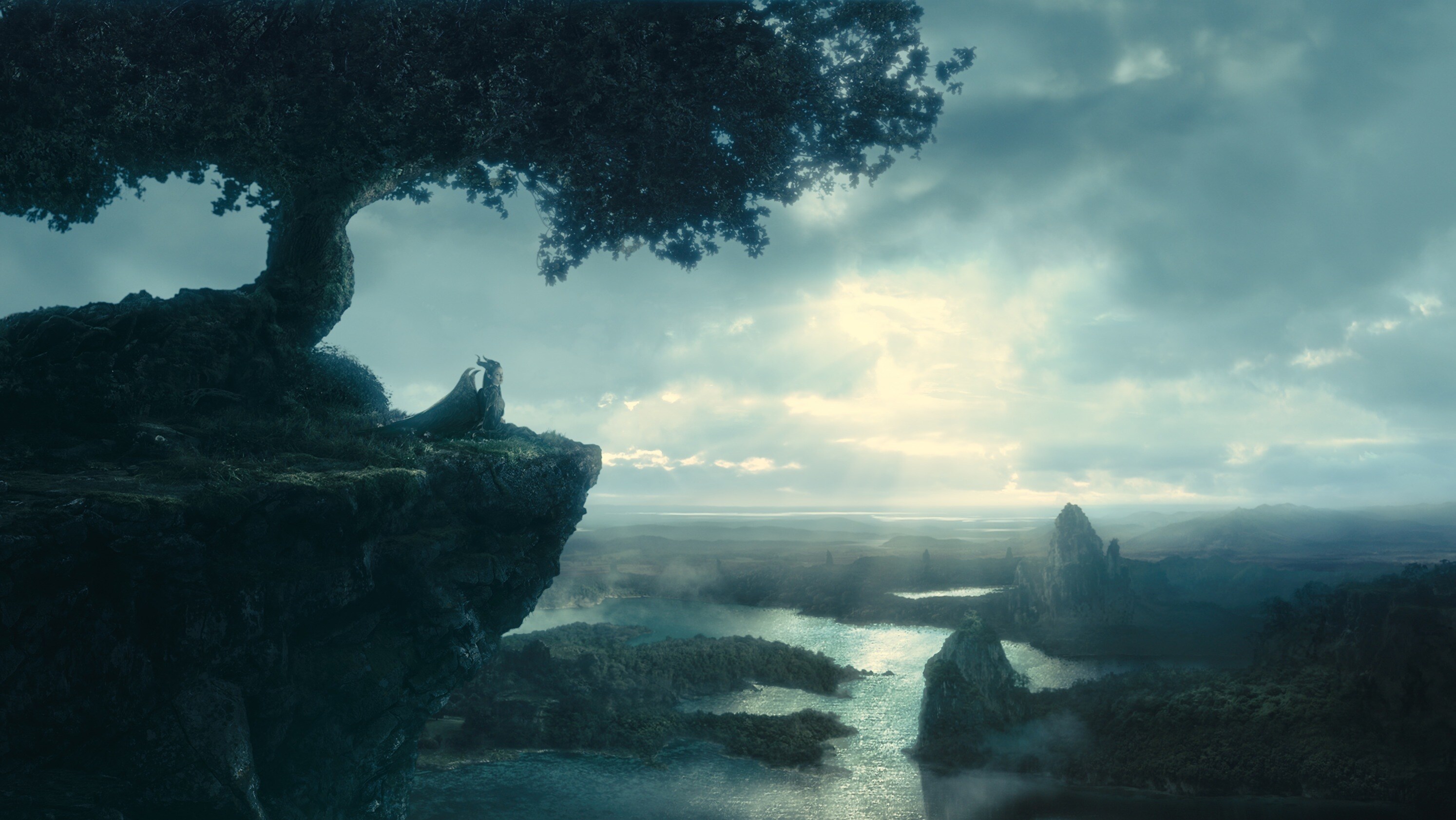 Angelina Jolie as Maleficent sitting under a tree overlooking the river or bay in the movie "Maleficent" 