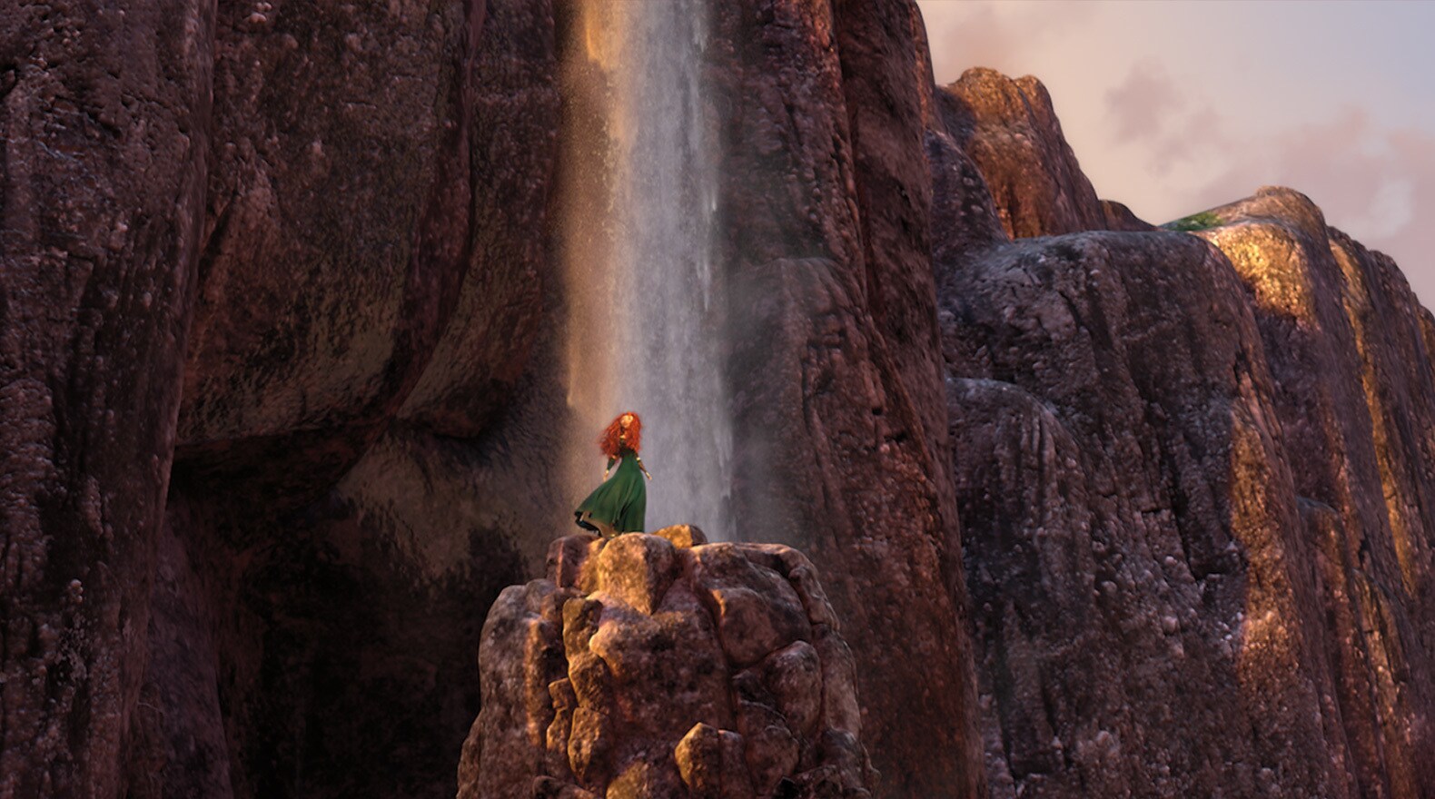 Merida, voiced by Kelly Macdonald, standing on a rock in front of the Fire Falls in the movie Brave