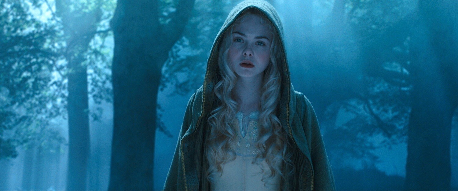 A hooded Elle Fanning as Aurora in the forest in the movie "Maleficent" 