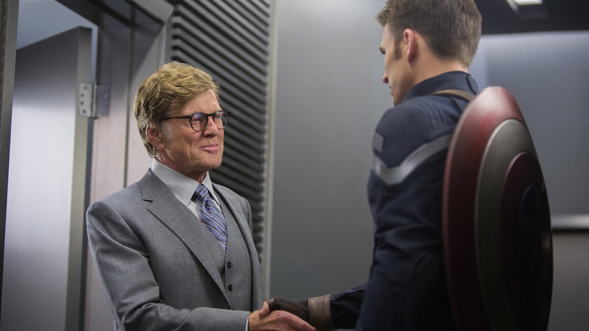 Actors Robert Redford (Alexander Pierce) and Chris Evans (Steve Rogers/Captain America) shake hands in Captain America: The Winter Soldier.