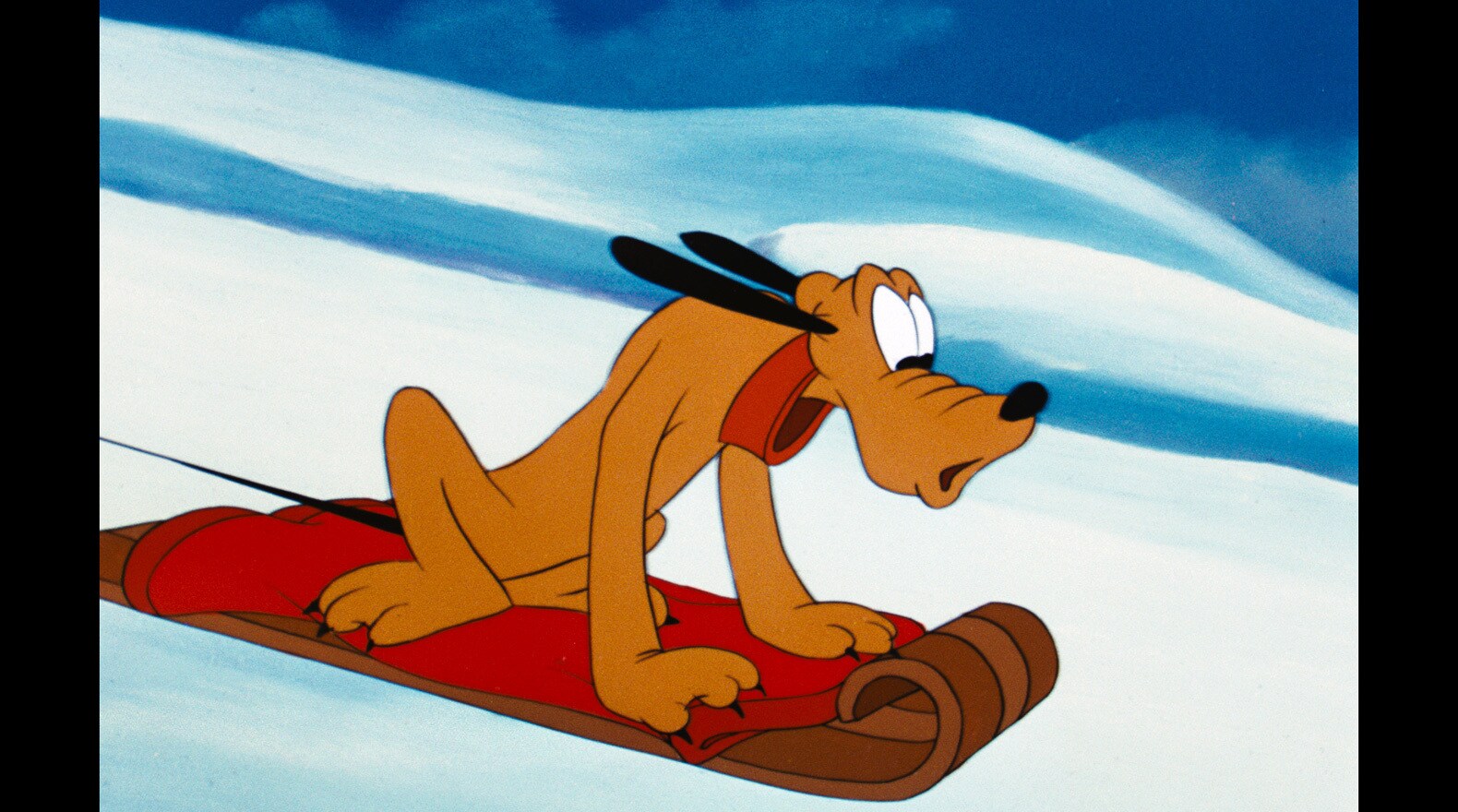 Pluto looks down the snow-covered mountain as he careens on a sleigh.